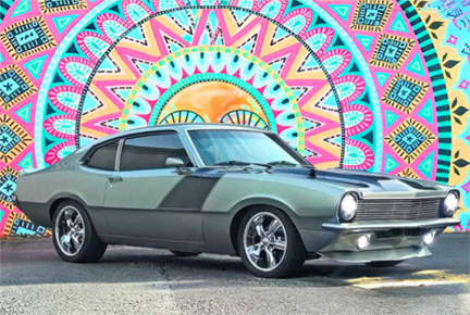 Silver Ford Maverick in front of a colorful mural